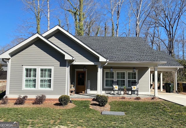 view of front facade with a porch, concrete driveway, roof with shingles, and a front lawn