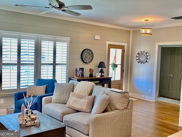 living area featuring baseboards, ceiling fan, visible vents, and wood finished floors