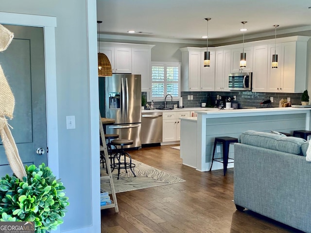 kitchen featuring tasteful backsplash, dark wood finished floors, appliances with stainless steel finishes, white cabinetry, and a sink