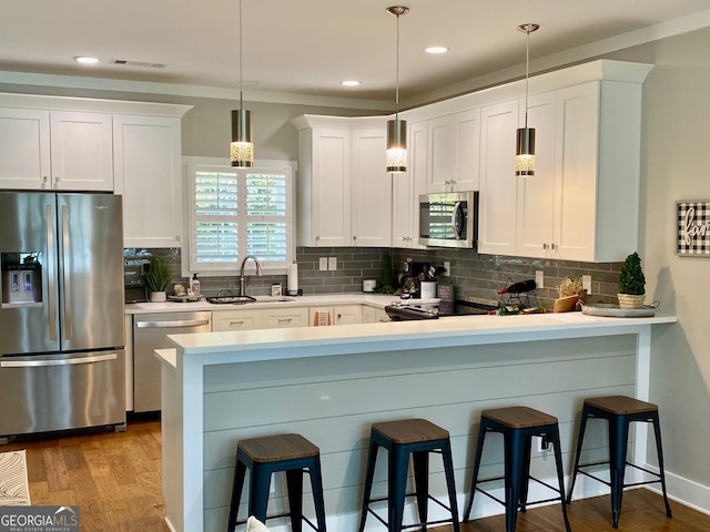 kitchen featuring stainless steel appliances, tasteful backsplash, visible vents, a sink, and a kitchen breakfast bar