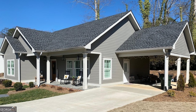 view of front of property featuring a shingled roof, covered porch, and concrete driveway