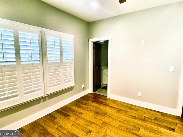 empty room featuring ceiling fan, baseboards, and dark wood-style flooring