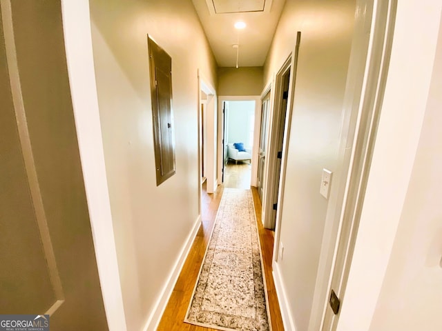 corridor featuring wood finished floors, attic access, and baseboards