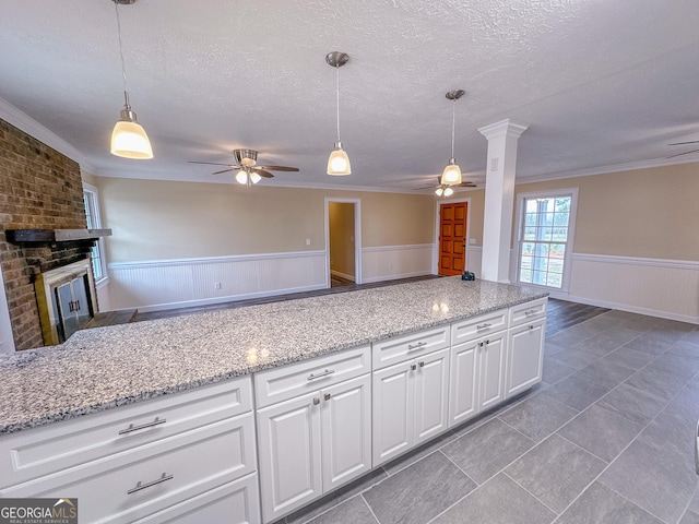 kitchen featuring a wainscoted wall, a fireplace, open floor plan, white cabinetry, and a textured ceiling