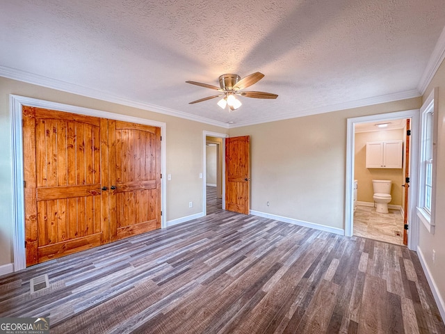 unfurnished bedroom with baseboards, visible vents, wood finished floors, and ornamental molding