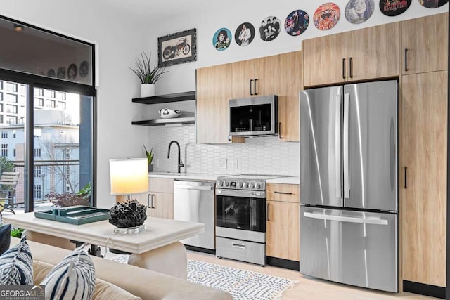 kitchen featuring decorative backsplash, stainless steel appliances, light countertops, open shelves, and a sink