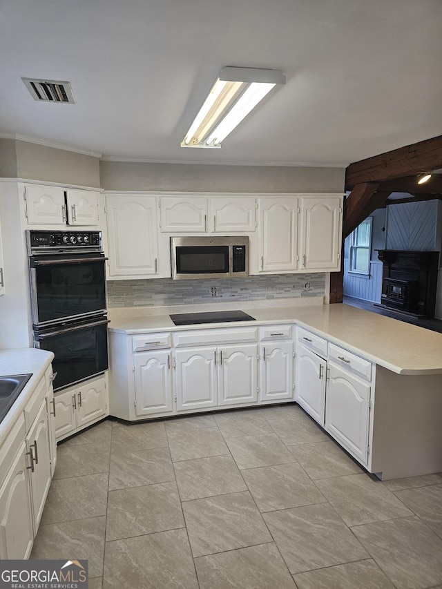 kitchen with a peninsula, black appliances, visible vents, and light countertops