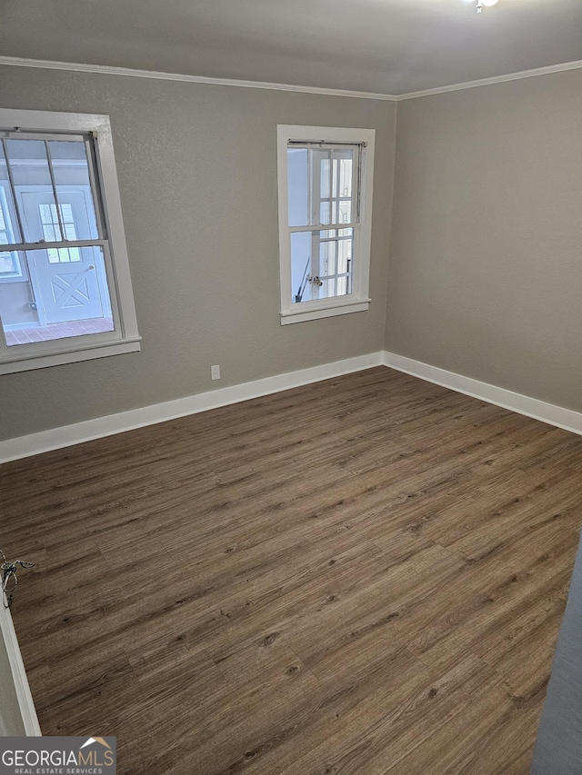 empty room with baseboards, ornamental molding, and dark wood finished floors