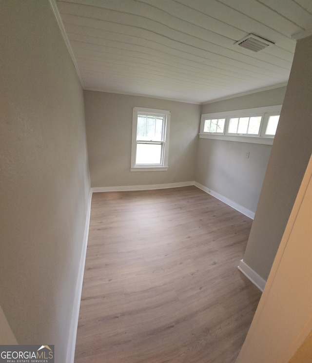 spare room with visible vents, crown molding, baseboards, and wood finished floors