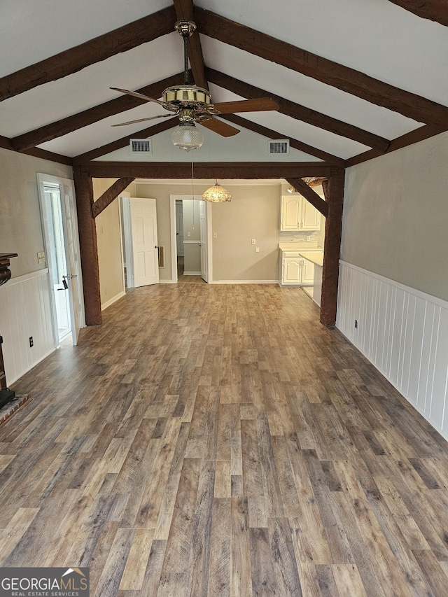 unfurnished living room featuring visible vents, wood finished floors, and wainscoting