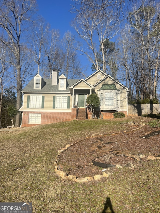 view of front facade featuring brick siding, a front yard, and fence