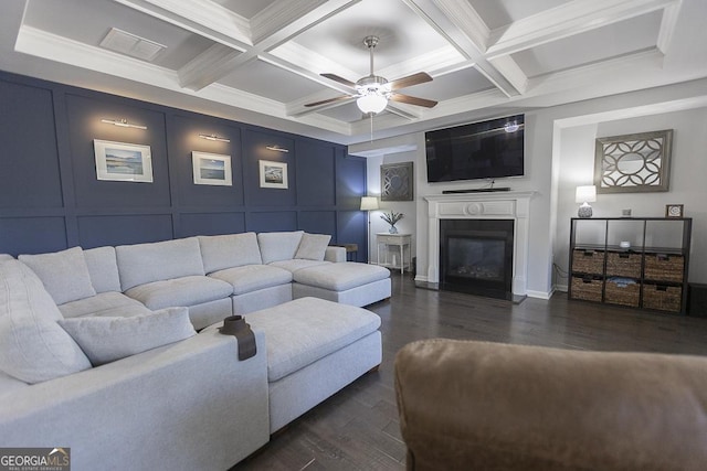 living room featuring a fireplace with flush hearth, beam ceiling, a decorative wall, and dark wood-style flooring