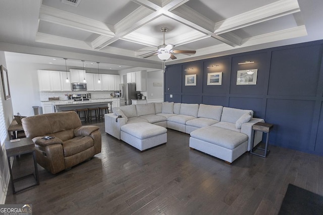 living area with a decorative wall, dark wood-type flooring, coffered ceiling, a ceiling fan, and beam ceiling