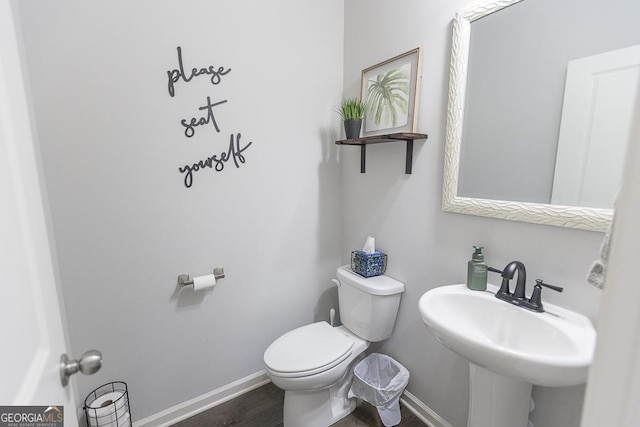 half bathroom featuring baseboards, a sink, toilet, and wood finished floors