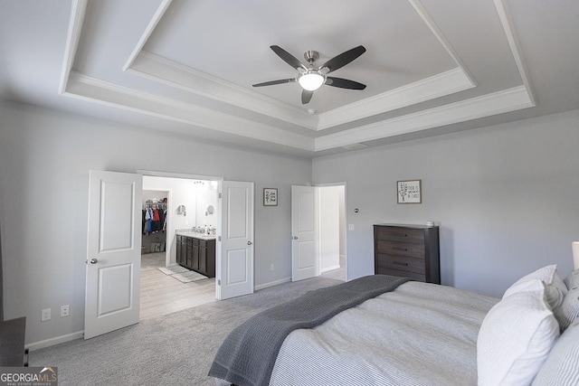 bedroom with a raised ceiling, a ceiling fan, light colored carpet, a spacious closet, and crown molding