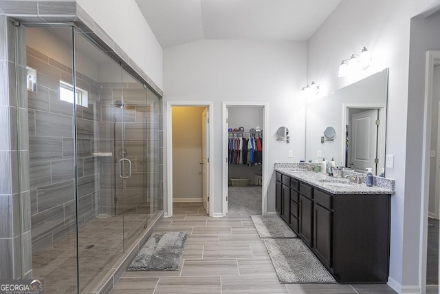 full bath with double vanity, a stall shower, vaulted ceiling, and a sink