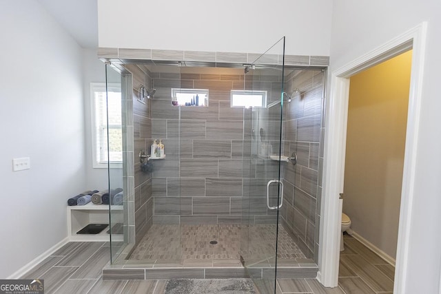 full bathroom featuring toilet, a shower stall, and baseboards