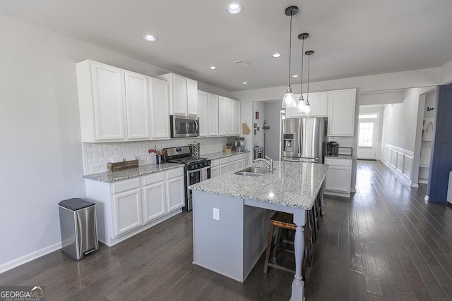 kitchen featuring appliances with stainless steel finishes, a sink, dark wood finished floors, and white cabinets