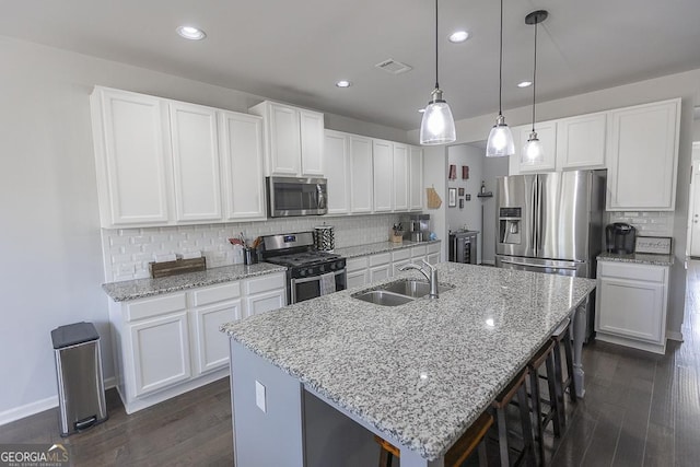 kitchen featuring visible vents, dark wood finished floors, appliances with stainless steel finishes, a kitchen island with sink, and a sink