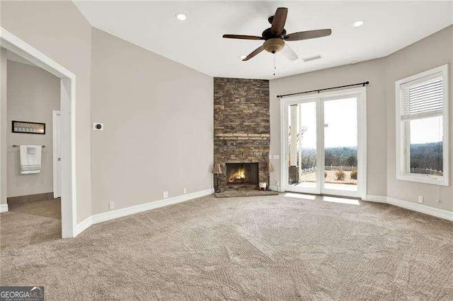 unfurnished living room with a stone fireplace, carpet, and baseboards