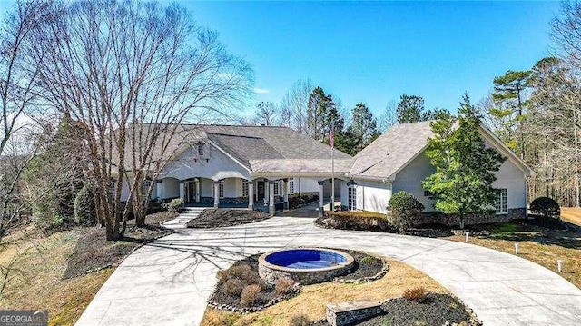 view of front of property with a porch, curved driveway, and stucco siding