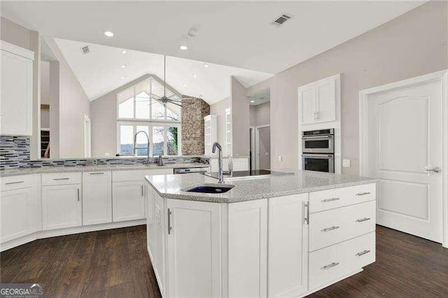 kitchen featuring double oven, visible vents, white cabinets, and light stone counters