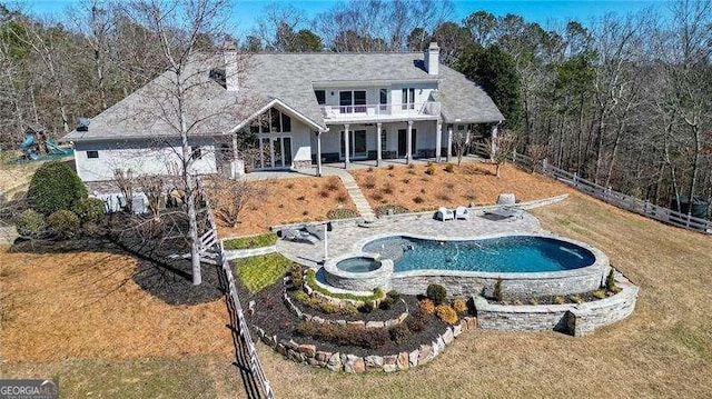 rear view of property featuring a patio, a balcony, fence, a yard, and an outdoor pool