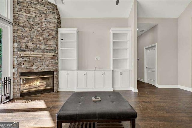 unfurnished living room featuring vaulted ceiling, a stone fireplace, baseboards, and wood finished floors