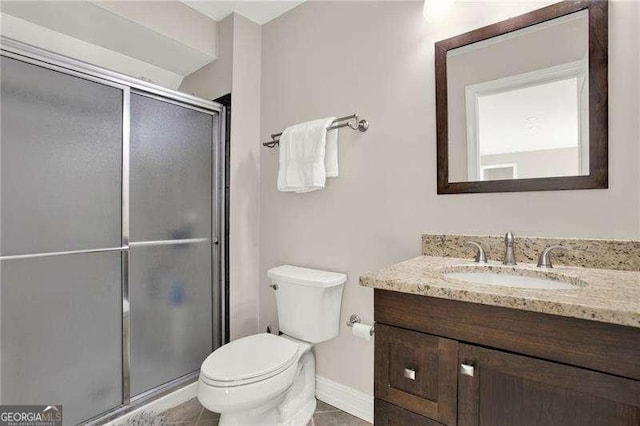 bathroom featuring toilet, a shower stall, vanity, baseboards, and tile patterned floors