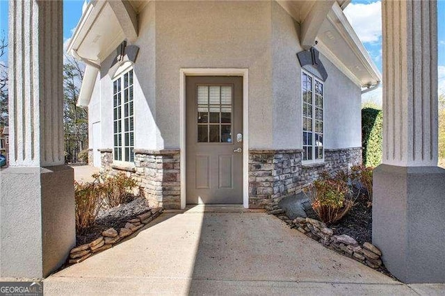 view of exterior entry featuring stone siding and stucco siding