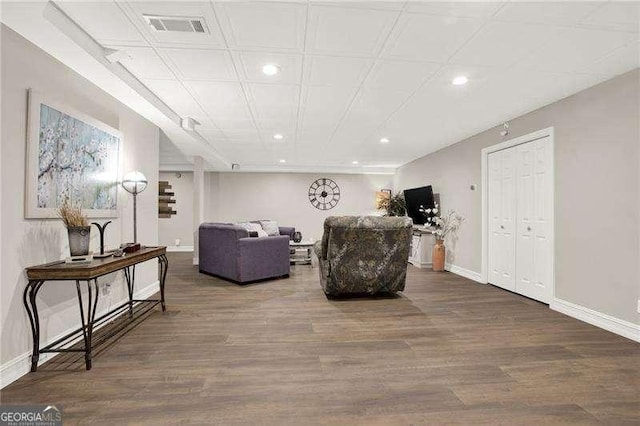 living area with wood finished floors, visible vents, and baseboards