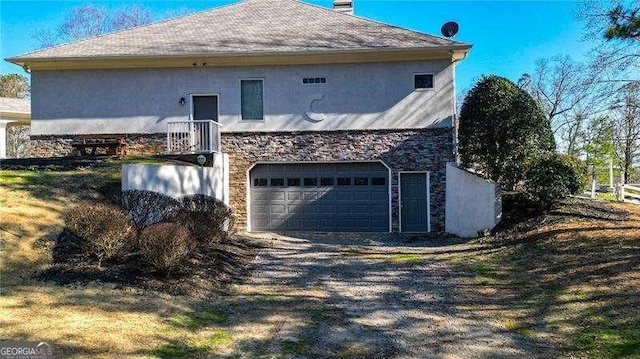 view of side of property featuring a garage, dirt driveway, and stucco siding