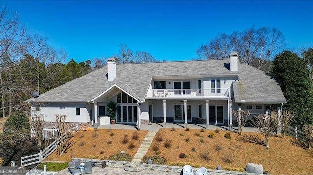 view of front of house featuring a chimney, a patio area, fence, and a balcony