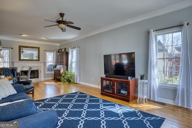 living room with baseboards, visible vents, a premium fireplace, ornamental molding, and wood finished floors