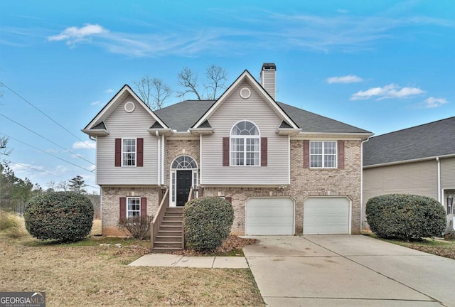 split foyer home with a garage, a chimney, concrete driveway, and brick siding