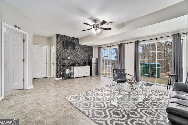 living room featuring ceiling fan, visible vents, and baseboards