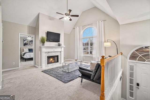 living room featuring baseboards, a ceiling fan, a premium fireplace, carpet flooring, and high vaulted ceiling