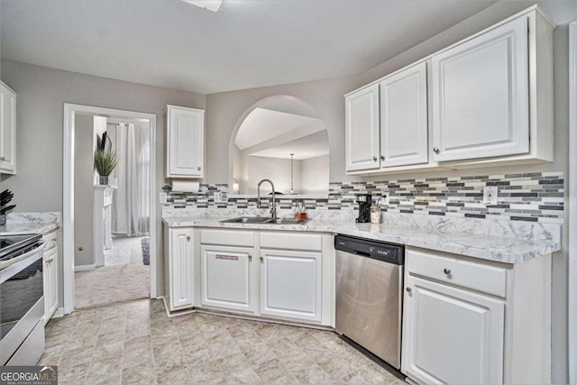 kitchen featuring arched walkways, a sink, white cabinets, appliances with stainless steel finishes, and tasteful backsplash