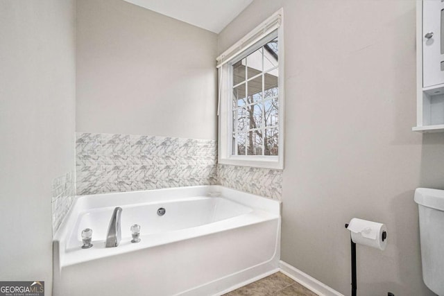 full bathroom featuring tile patterned flooring, baseboards, toilet, and a bath