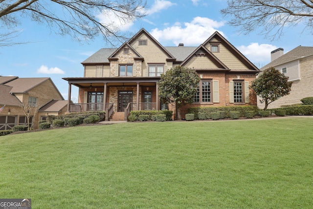craftsman-style home featuring covered porch, a front lawn, and stone siding