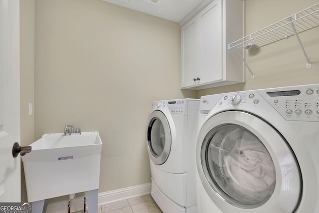 washroom featuring cabinet space, washing machine and clothes dryer, light tile patterned floors, and baseboards