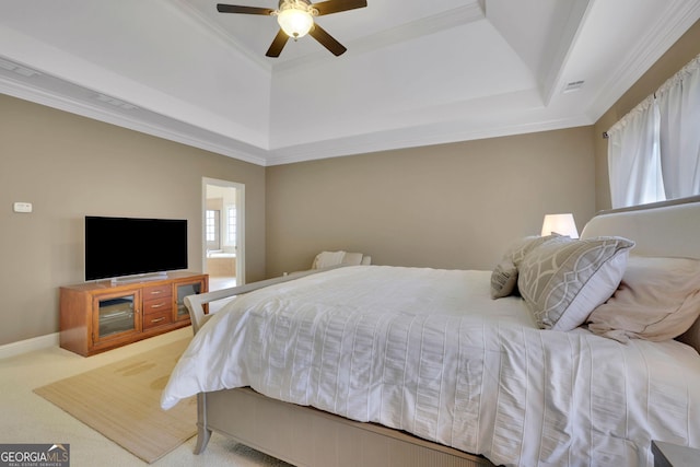 bedroom featuring a raised ceiling, ornamental molding, carpet floors, and a ceiling fan