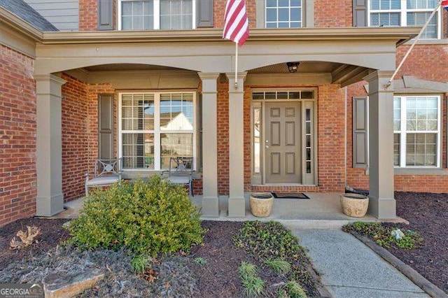 view of exterior entry with covered porch and brick siding