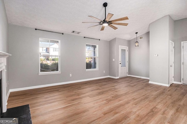 unfurnished living room with visible vents, lofted ceiling, a fireplace, and a ceiling fan