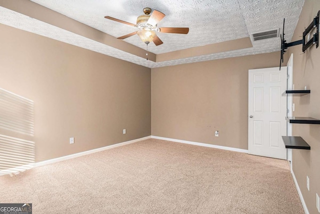 unfurnished room featuring a tray ceiling, carpet floors, visible vents, and ceiling fan