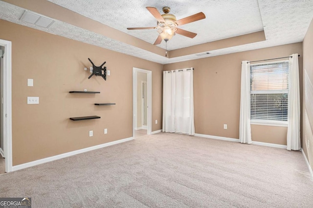 interior space with visible vents, baseboards, carpet, a tray ceiling, and a textured ceiling