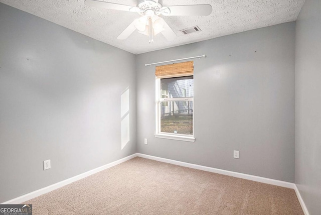 unfurnished room featuring a ceiling fan, carpet flooring, baseboards, and visible vents