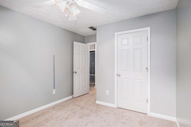 unfurnished bedroom with visible vents, carpet floors, a textured ceiling, and baseboards