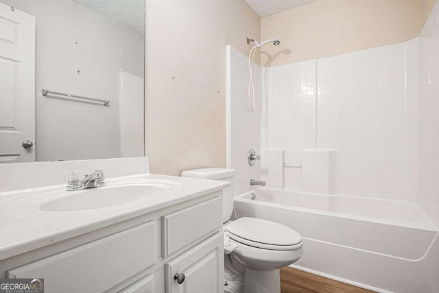 bathroom featuring vanity, wood finished floors, a textured ceiling, bathing tub / shower combination, and toilet