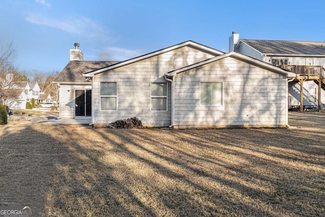 back of property with a yard and a chimney